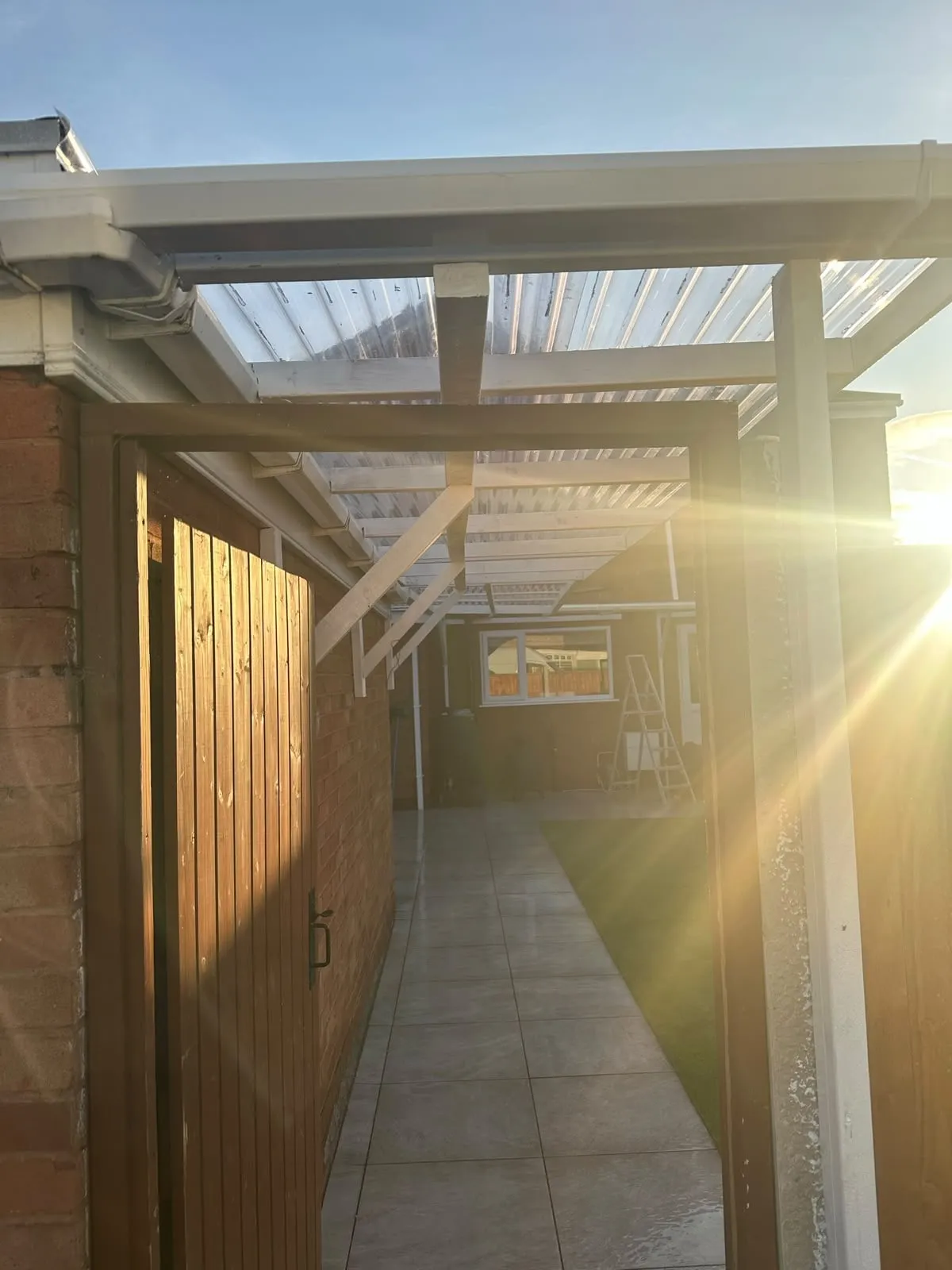 Covered walkway with a pergola roof along the side of a house